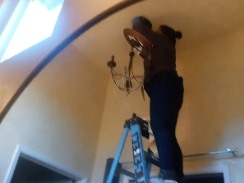 Electrician installing a chandelier in a Genoa residence